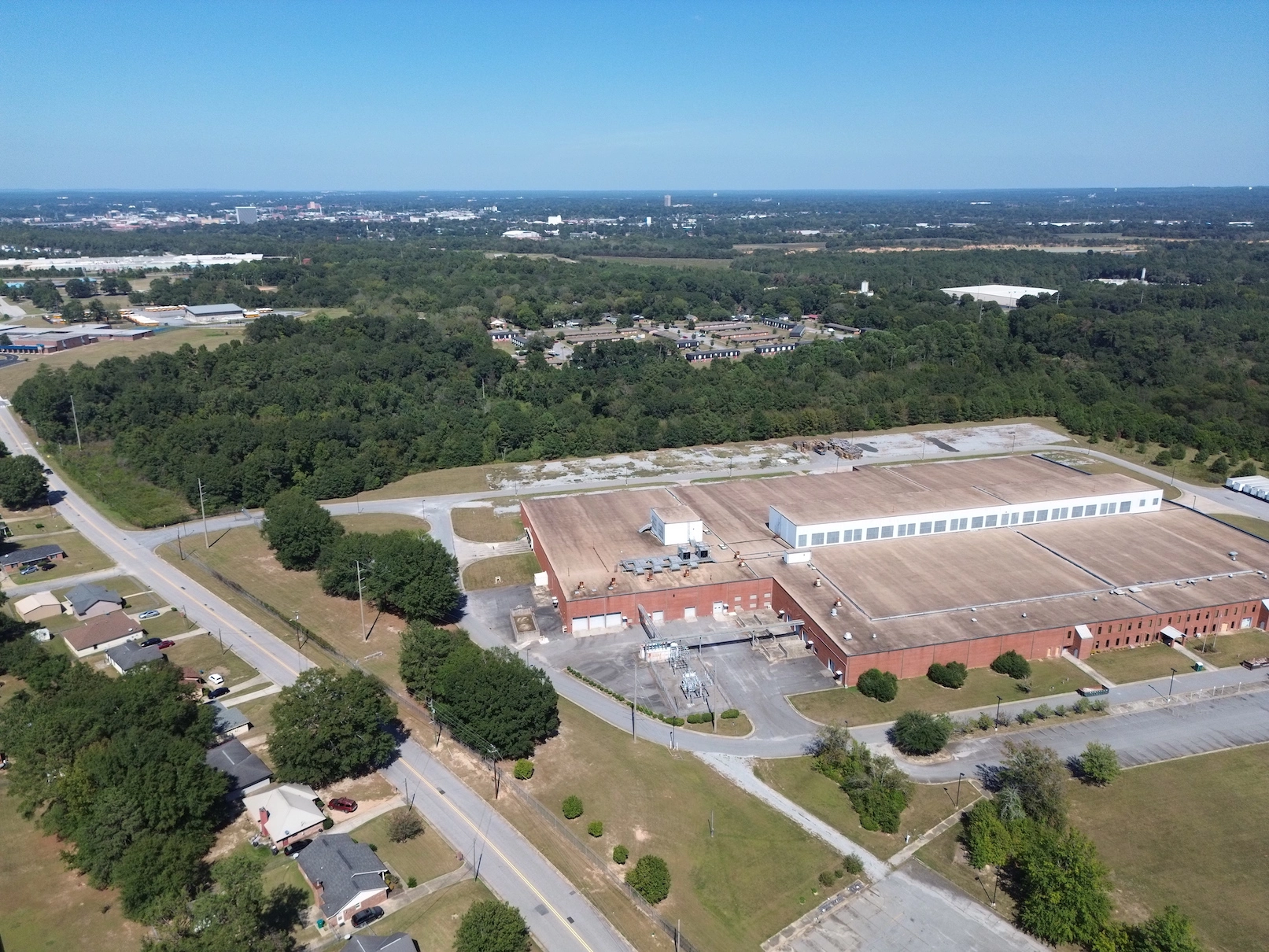 Image of a warehouse, trees, neighborhood and skyline
